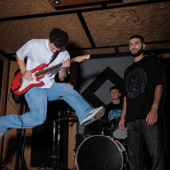 FROST Clothing oversized graphic tee inspired by vintage rock band merch. Fall Winter 25 collection titled 'ROCKSTAR'. Person playing guitar while jumping in mid air.
